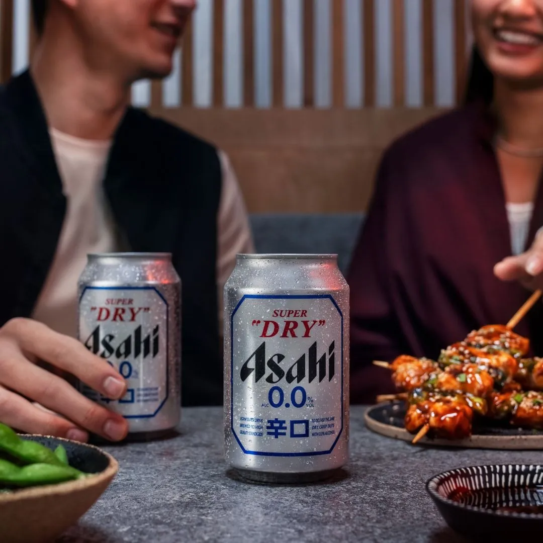 Deux canettes d'Asahi Super Dry 0.0 sur une table d'izakaya, avec des brochettes