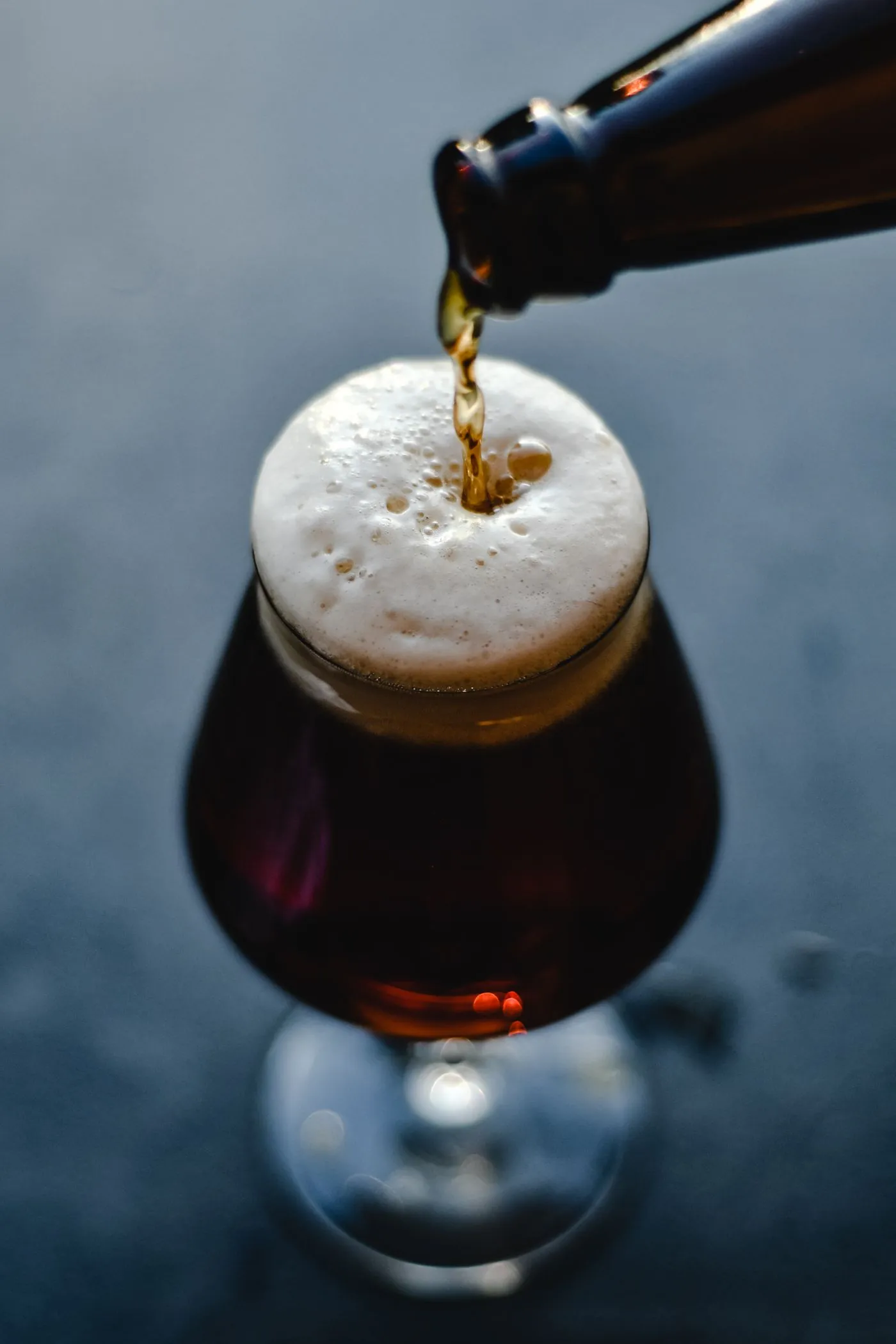Bière noire qui se verse dans un verre, avec de la mousse